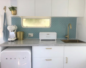 seafoam lantern stick on tile in a caravan with gold touches and white appliances